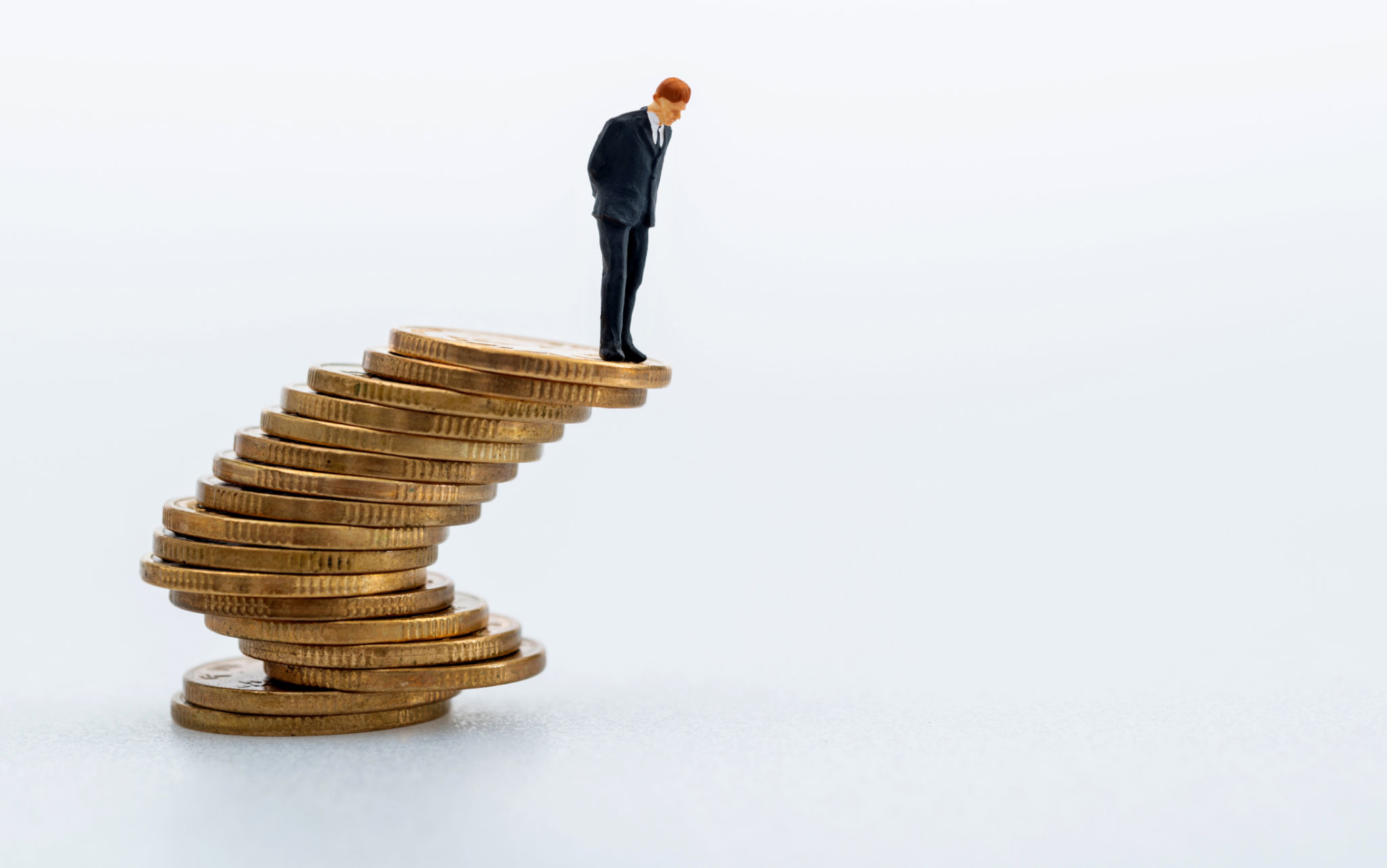 Businessman figurine standing on stack of coins.